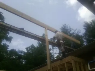 Carpenter setting a ridge beam over a new addition frame — Ice Dam Removal by Roofing Brothers in Destin