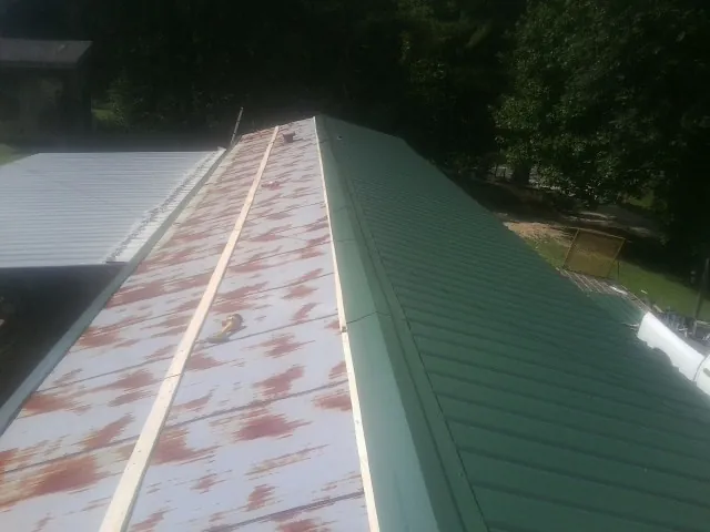 Old rusted panels beside newly installed green metal roofing — Wind Damage Roof Repair by Roofing Brothers in Destin