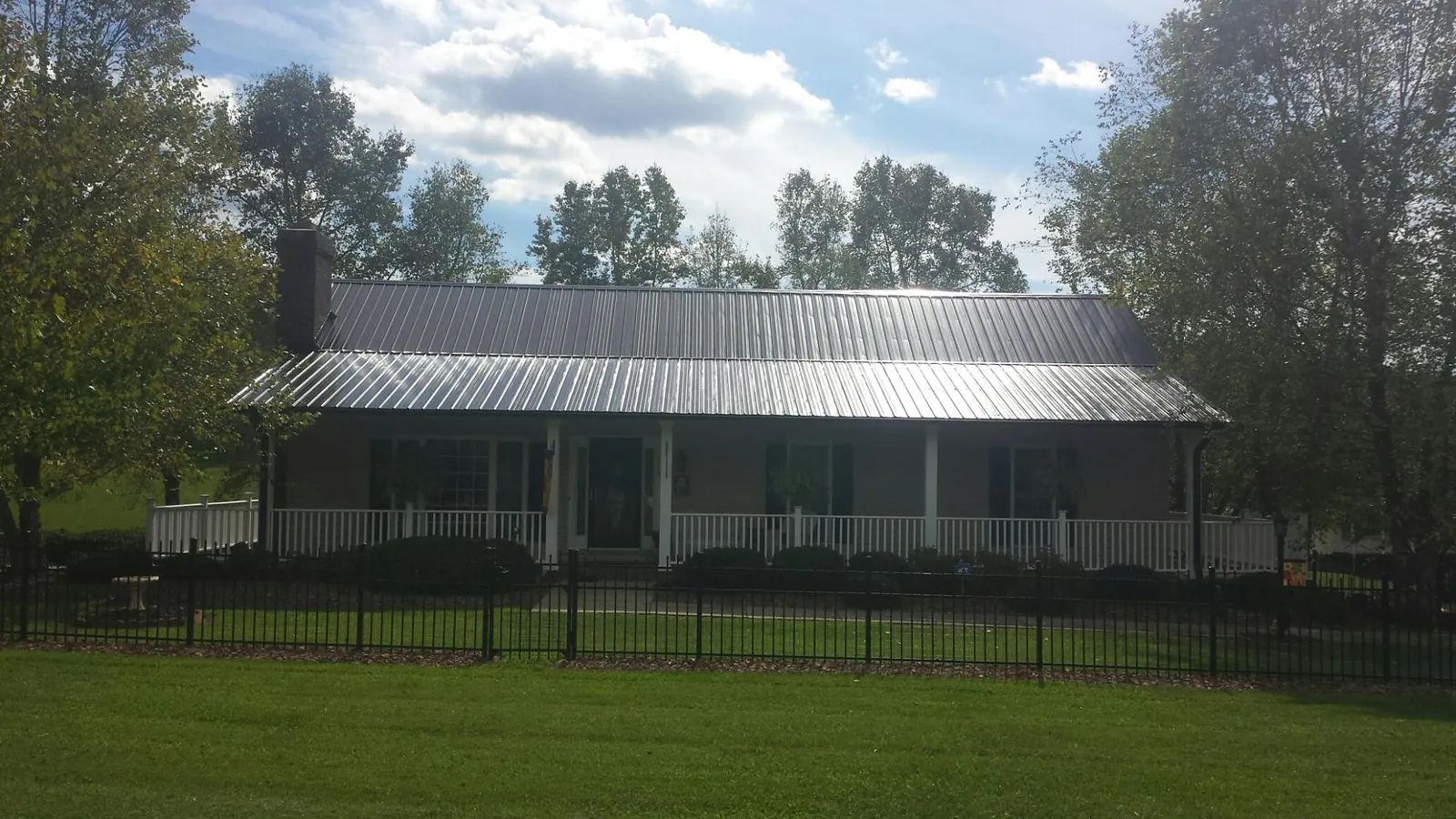 Gray metal roof on a brick ranch with a full width front porch — Gutter Guard Installation work by our crew in Destin